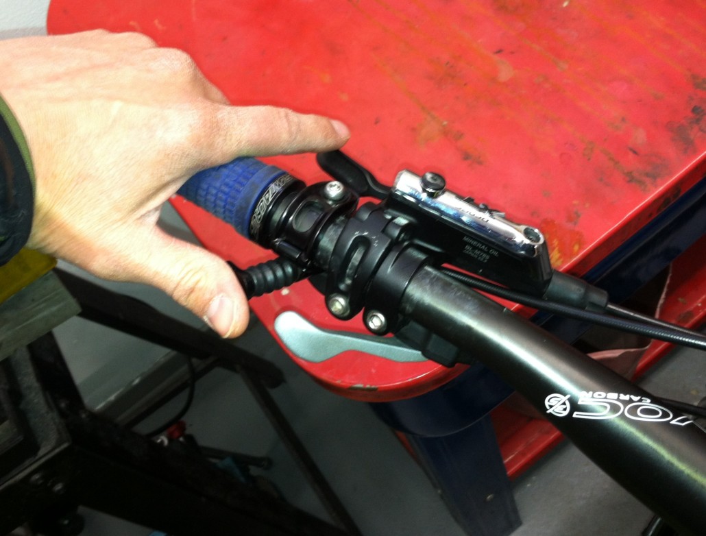 These photos show the remote lever mounted on the left side and under the bar. The top photo shows the lever actually mounted right next to the grip (sometimes necessary for small hands). The bottom photo shows the lever mounted between the brake and shifter. The rider will not be able to reach the front shifter in either case, but that's OK (reasons in text)... Notice the two different styles of lever.
